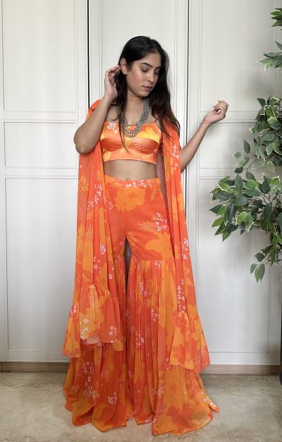 Orange Satin Silk Printed Blouse with matching Georgette Printed Sharara and Georgette Cape with Crystal work.
